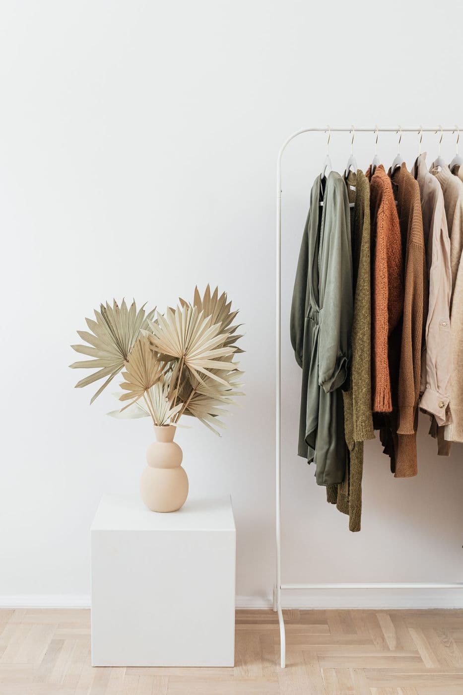 Knitwear on a clothes rail beside dried palm leaves