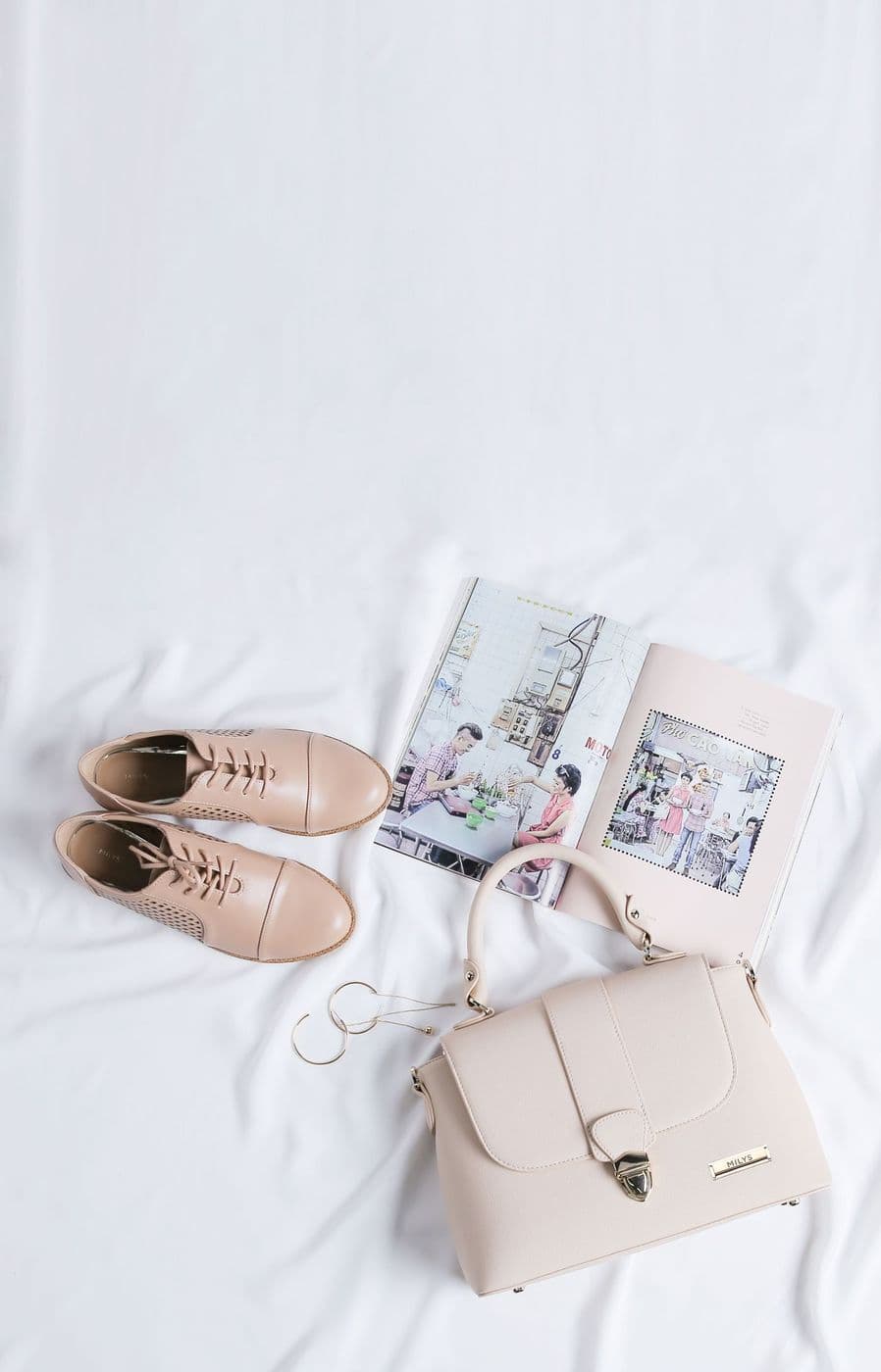 Beige shoes and a handbag laid out on white linen